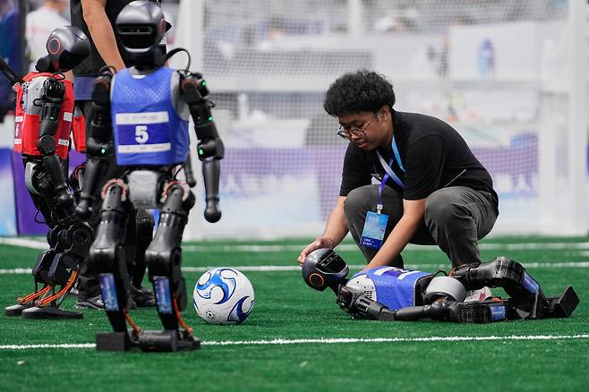 지난 15일 로봇운동회 5대5 축구 경기에서 쓰러진 휴머노이드를 엔지니어가 살피고 있다. /AP연합뉴스