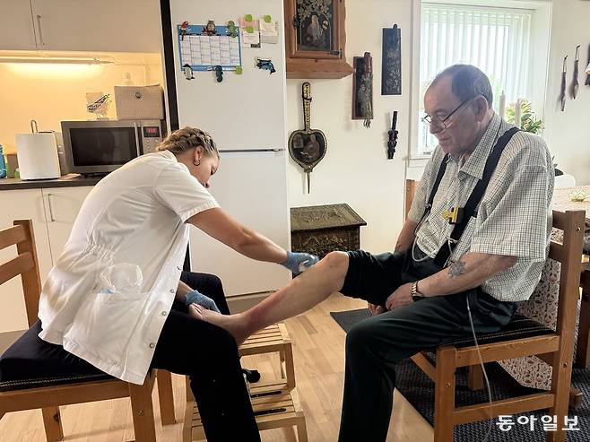 4일(현지 시간) 덴마크 코펜하겐시 소속 방문간호사 멧테 비스고르 씨(왼쪽)가 80대 환자 포울 소렌센 씨의 자택을 방문해 상처 부위를 치료하고 있다. 소렌센 씨는 호흡 기능이 저하돼 산소호흡기를 착용해야 하지만 병원에 입원하지 않고 방문간호 서비스를 받으며 자택에서 치료를 받고 있다. 코펜하겐=전채은 기자 chan2@donga.com