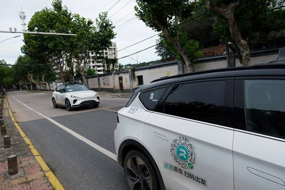 지난해 7월 19일 중국 IT기업 바이두의 로보택시 서비스인 아폴로 고의 자율주행 차량(로보택시)이 중국 후베이성 우한의 도로변에 주차된 다른 아폴로 고 로보택시를 지나가고 있다. 로이터=연합뉴스