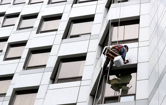 서울 도심의 고층빌딩 외벽을 청소하고 있는 작업자의 모습. 장진영 기자