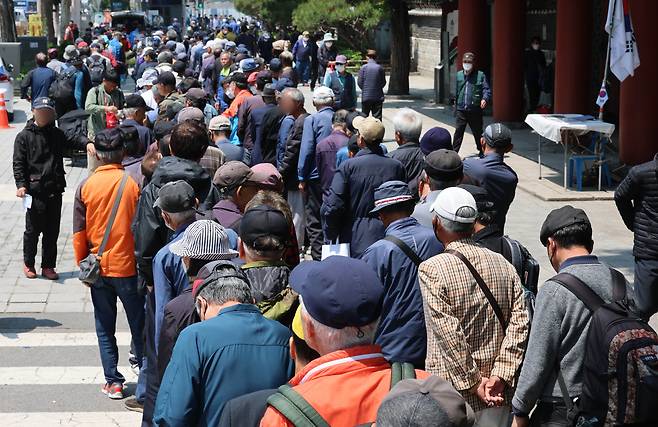 Elderly citizens wait in line for a free lunch service at a public park in Jongno District, central Seoul, on May 12. [NEWS1]