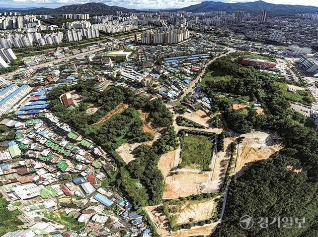 의정부시 금오동은 제5군수지원여단 부지로 인해 수십년간 개발이 제한돼 주민들이 불편을 감내해 왔다. 부대가 떠난 뒤에도 토양 오염과 규제로 활용이 지연되며 마을은 여전히 멈춰 서 있다. 사진은 좁은 골목에 낡은 단독주택이 빼곡한 금오동과 그 너머 병풍처럼 둘러선 민락동의 고층 아파트 단지 모습. 조주현기자