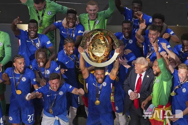 [이스트 러더퍼드=AP/뉴시스] 첼시(잉글랜드) 선수들이 13일(현지 시간) 미 뉴저지주 이스트 러더퍼드의 메트라이프 스타디움에서 열린 2025 국제축구연맹(FIFA) 클럽 월드컵 정상에 올라 트로피를 들고 도널드 트럼프 미국 대통령과 함께 환호하고 있다. 첼시는 결승에서 파리 생제르맹(PSG, 프랑스)을 3-0으로 완파하고 우승컵을 들어 올렸다. 2025.07.14.