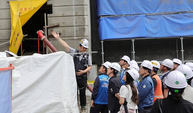 Kim Ju-young, head of the Democratic Party’s task force on industrial accident prevention, and Park Hae-cheol, the task force’s secretary, listen to a briefing from officials during a visit to a DL Construction apartment construction site in Uijeongbu, Gyeonggi, on Aug. 14, where a worker recently died after a fall. [YONHAP]