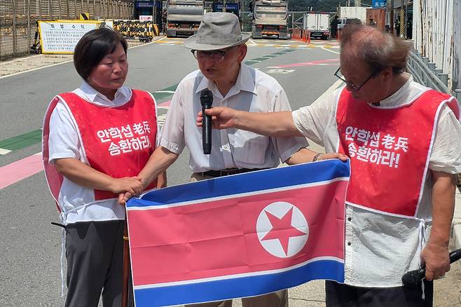 20일 오전 경기도 파주시 통일대교 남단에서 북한 송환을 요구한 비전향장기수 안학섭(가운데)씨가 인공기를 펼쳐 들고 있다. /연합뉴스