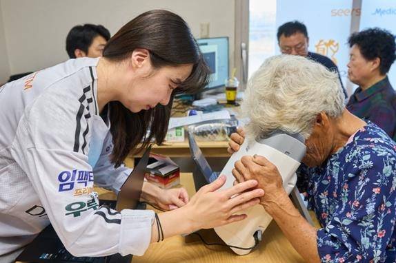 대부도 주민이 AI 실명질환 진단 솔루션 '위스키'와 안저카메라 '옵티나 제네시스'를 활용해 안저 상태를 확인하고 있다. [대웅제약 제공]