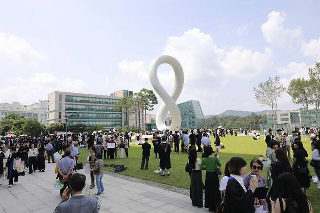 ▲ 가천대 졸업생, 학부모들이 21일 대학 가천관 앞에 세워진 상징물 '무한대상' 앞에서 졸업 기념사진을 찍고 있다. /사진제공=가천대학교