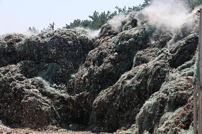 ▲ 아파트 2층 높이로 쌓인 폐그물에서 하얀 연기가 피어오르고 있다. /이재민 기자 leejm@incheonilbo.com