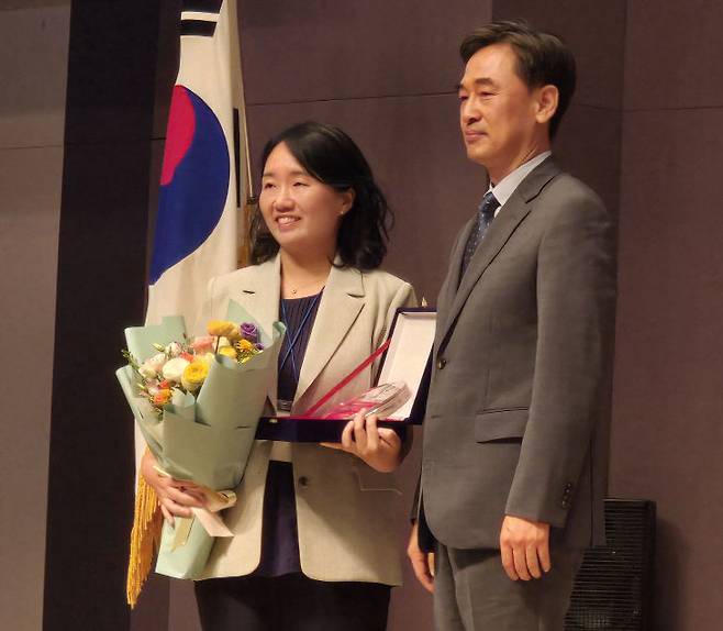 천재현 헌법재판소 공보관이 헌법재판소를 대표해  심석태 한국언론법학회장으로부터 제24회 판결 수상을 하고 상패와 꽃다발을 받고 있다,