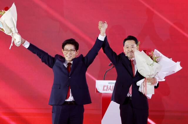 22일 충북 청주시 흥덕구 청주 오스코에서 열린 국민의힘 제6차 전당대회에서 결선에 진출한 김문수, 장동혁 당 대표 후보가 꽃다발을 건네받은 뒤 손을 들어 올리고 있다. 연합뉴스
