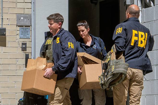 FBI 요원들이 22일(현지 시각) 워싱턴 존 볼턴 전 국가안보보좌관의 사무실을 압수수색해 자료를 넣은 상자를 들고 나오고 있다.AP 연합뉴스