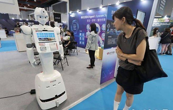 지난 1일 대만 타이베이에서 열린 ‘AI 웨이브 쇼’에서 한 여성이 인공지능(AI) 기술을 활용한 안내 로봇을 바라보고 있다. ⓒ AP/뉴시스