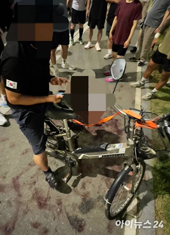 50대 남성이 자신이 키우는 반려견을 전기자전거에 줄을 매달아 끌고 가다가 시민들의 저지에 멈춰서고 있다 [사진=독자]