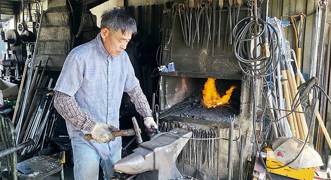 폭염경보가 발효된 25일 오전 광주 광산구 송정매일시장 내 60여년 전통의 송정대장간에서 최종호(61) 대장공이 달아오른 화덕 앞에서 단조 작업을 하고 있다./주성학 기자