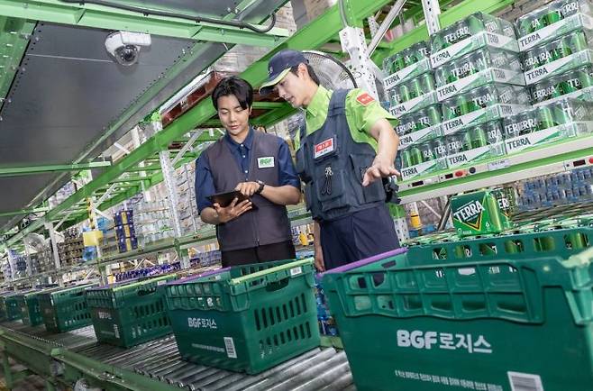 BGF로지스 직원과 에스원 근무자가 물류 추적 시스템을 확인하고 있다. 에스원
