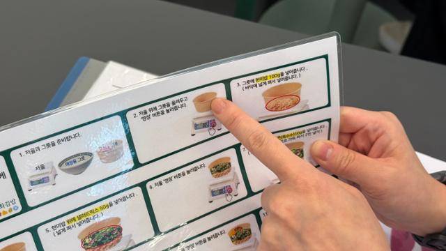 18일 서울 서대문구 이화여대 내 이수매니지먼트 식당에서 직원 교육을 담당하는 황영우 팀장이 '연두부튀김 포케 만들기' 지침서에 대해 설명하고 있다. 발달장애 근로자가 쉽게 이해할 수 있게 15단계로 순서가 나눠져 있다. 문지수 기자