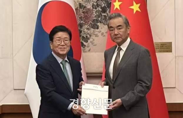 이재명 대통령 특사단 단장인 박병석 전 국회의장(왼쪽)이 24일(현지시간) 베이징 댜오위타이 국빈관 12호각에서 왕이 중국 공산당 외사판공실 주임 겸 외교부장을 만나 이 대통령이 시진핑 중국 국가주석에게 보낸 친서를 전달하고 있다. 한국 외교부 제공