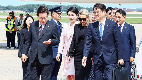 한미정상회의 참석차 미국을 방문한 이재명 대통령이 24일(현지시간) 워싱턴DC 앤드루스 통합기지에 도착해 영접나온 조슈아 킴 대령(이 대통령 오른쪽)으로부터 전달받은 기지방문기념 코인을 살펴보고 있다. 김현동 기자