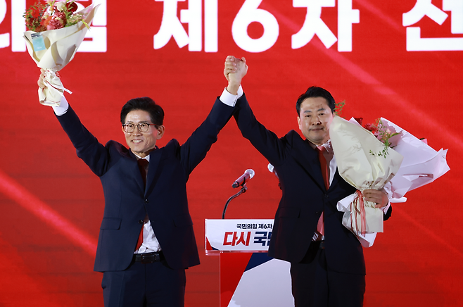 22일 충북 청주시 흥덕구 청주오스코에서 열린 국민의힘 제6차 전당대회에서 결선에 진출한 김문수, 장동혁 당대표 후보가 꽃다발을 받은 뒤 맞잡은 손을 들어 올리고 있다. ⓒ 연합뉴스