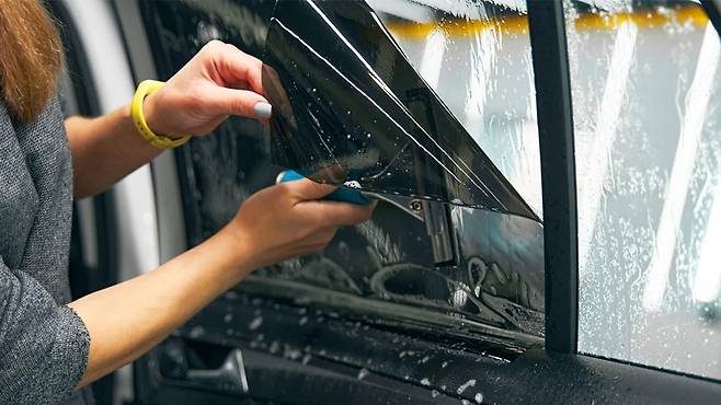 유리에 썬팅 필름 시공 중인 차량