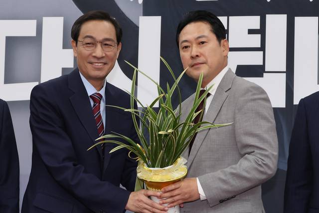 우상호(왼쪽) 대통령실 정무수석이 27일 국회 본청을 찾아 장동혁(오른쪽) 국민의힘 신임 당대표를 예방해 이재명 대통령이 보낸 축하난을 전달하고 있다.<연합뉴스 사진>
