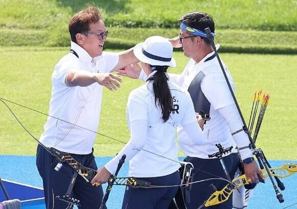 박성수 감독(사진 맨 왼쪽)이 2024년 8월 2일(현지시각) 프랑스 파리 레쟁발리드에서 열린 2024 파리올림픽 양궁 혼성 단체 독일과의 결승전에서 승리한 한국 김우진과 임시현을 환한 미소로 맞이하고 있다. 연합뉴스