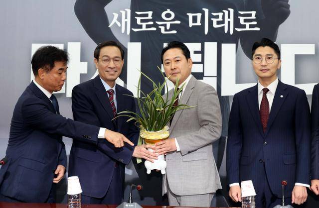 우상호(왼쪽 두 번째) 대통령실 정무수석과 장동혁 (왼쪽 세 번째) 신임 국민의힘 대표가 27일 국회 국민의힘 대표실에서 이재명 대통령이 선물한 축하 난을 들고 기념촬영을 하고 있다. 뉴시스