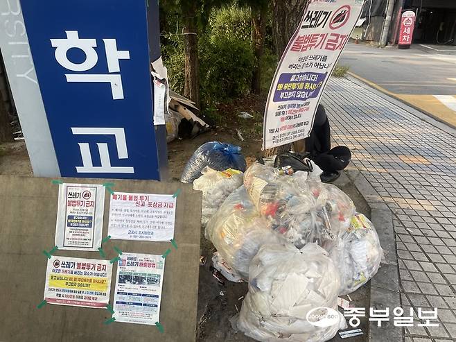 지난 24일 군포 당정역 1번 출구 인근 공터에 불법투기된 생활쓰레기 더미와 함께 '쓰레기 불법투기 금지' 경고문과 안내문이 붙어 있다. 손용현 기자