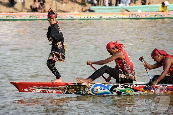 인도네시아 리아우주 쿠안탄강에서 열린 파추 잘루르(Pacu Jalur) 전통 보트 경주 축제중 뱃머리에서 춤을 추며 SNS에서 화제를 모은 11세 소년 레이얀 아르칸 디카(왼쪽)가 공연을 선보이고 있다. 2025.8.21 ⓒ AFP=뉴스1