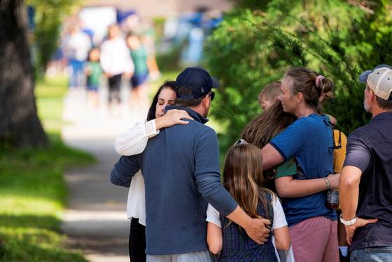 미국 미네소타주 미니애폴리스에 있는 ‘수태고지 가톨릭 학교’에서 총격 사건이 발생한 후 경찰 바리케이드 밖에서 해당 학교의 학생이 그의 가족과 포옹하고 있다. 로이터=연합뉴스