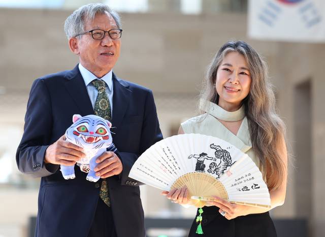 유홍준 국립중앙박물관장(왼쪽)과 넷플릭스 오리지널 애니메이션 '케이팝 데몬 헌터스'의 매기 강 감독이 21일 서울 용산구 국립중앙박물관에서 선물을 주고 받은 뒤 기념촬영을 하고 있다. 연합뉴스