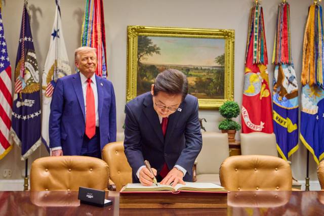 이재명 대통령이 25일(현지시간) 미국 워싱턴 DC 백악관에서 도널드 트럼프 미국 대통령이 지켜보는 가운데 방명록을 작성하고 있다. 대통령실사진공동취재단