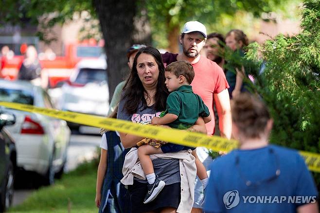 27일(현지시간) 미국 미네소타주 미니애폴리스 초등학교에서 발생한 총기사건 후 한 아이가 아이를 끌어안고 사건 현장을 바라보고 있다.   [로이터 연합뉴스 자료사진. 재배포 및 DB 금지]