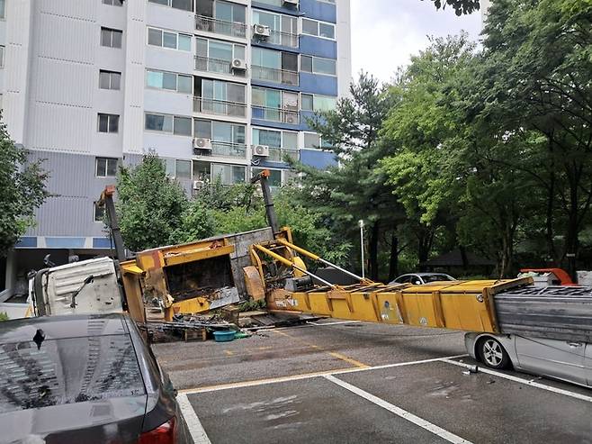 1일 오전 성남시 분당구 정자동의 한 아파트 단지에 이사용 사다리차가 쓰러져 승용차가 깔려 있다. 사진=경기도소방재난본부