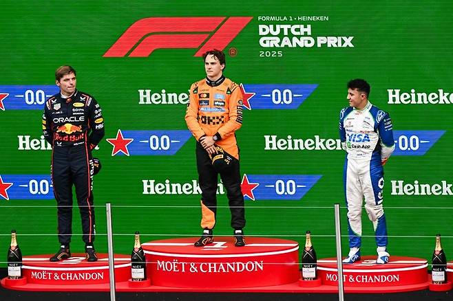 2025년 8월 31일 네덜란드 서부 잔드보르트 서킷에서 열린 포뮬러 원 네덜란드 그랑프리 이후 시상대에서 준우승을 차지한 레드불 레이싱의 네덜란드 드라이버 맥스 페르스타펜, 우승을 거둔 맥라렌의 호주 드라이버 오스카 피아스트리, 3위를 기록한 RB의 프랑스 드라이버 이사크 하자르가 함께 기뻐하고 있다.&nbsp;