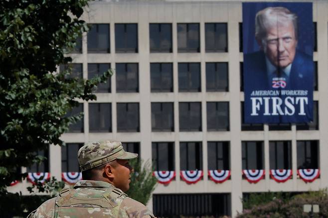 2025년 8월 27일, 미국 워싱턴 D.C. 노동부 건물에 걸려 있는 도널드 트럼프 미국 대통령 현수막을 지나 내셔널 몰을 순찰하는 주 방위군. /연합뉴스
