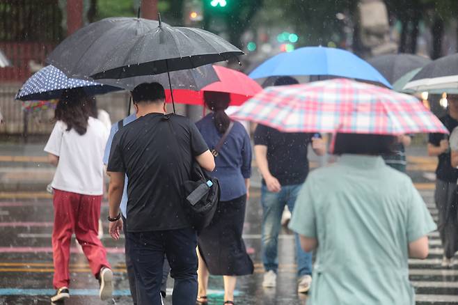 비가 내린 13일 서울 종로구 광화문 네거리에서 우산을 쓴 시민들이 길을 건너고 있다. [사진 = 연합뉴스]