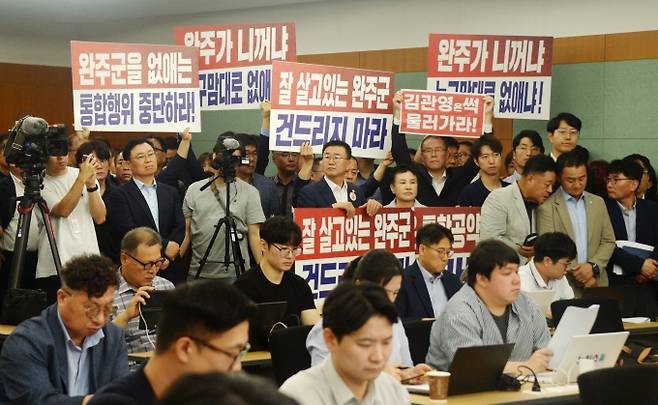 ▲지난 7월 21일 완주군의회 의원들을 비롯한 완주·전주 통합을 반대하는 군민들이 전북 전주시 전북특별자치도청 기자회견장에서 열린 완주-전주 통합과 관련한 기자회견을 청취하며 손피켓을 들고 있다./사진=뉴시스