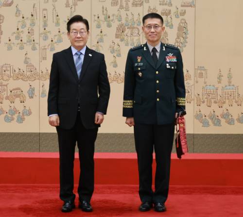 이재명 대통령이 2일 서울 용산 대통령실 청사에서 열린 대장 진급·보직 신고식에서 김규하 육군참모총장의 삼정검에 수치를 달아준 뒤 기념촬영을 하고 있다. 연합뉴스