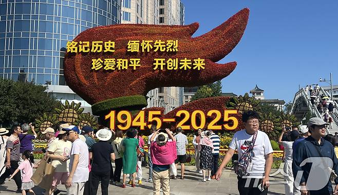 중국의 항일전쟁 및 세계 반파시스트 전쟁(제2차 세계대전) 승리 80주년(전승절) 기념 열병식을 이틀 앞둔 1일 오전 중국 베이징 천안문 인근 거리에 설치된 꽃 조형물 앞에서 행인들이 기념 사진을 찍고 있다. 2025.9.1/뉴스1 ⓒ News1 박정호 기자