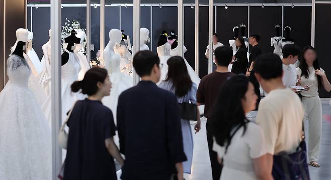 지난 7월 6일 서울 강남구 삼성동 코엑스에서 열린 2025 추계 웨덱스 웨딩 박람회에서 예비 부부들이 전시된 드레스를 살펴보고 있다. 기사 내용과 직접적인 관련 없음. /뉴스1