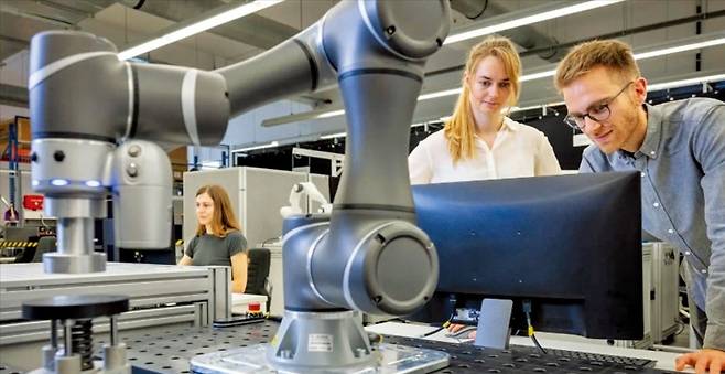 < 로봇 팔 시험하는 뮌헨공대 연구진 > 뮌헨공대 로봇·기계지능연구소 연구원들이 산업용 로봇 팔의 반응과 안전성을 시험하고 있다. 로봇·기계지능연구소는 올해 7월 로봇의 민감도를 수치화해 비교할 수 있는 인공지능(AI) 기반 평가 체계를 개발했다. 사람과 함께 일하는 휴머노이드·소프트 로봇에도 적용할 수 있다.  뮌헨공대 제공