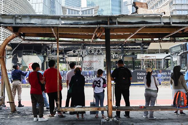 2일(현지시간) 인도네시아 자카르타에서 시민들이 최근 격화한 반정부 시위로 불에 탄 버스정류장 앞에 서 있다. 로이터연합뉴스