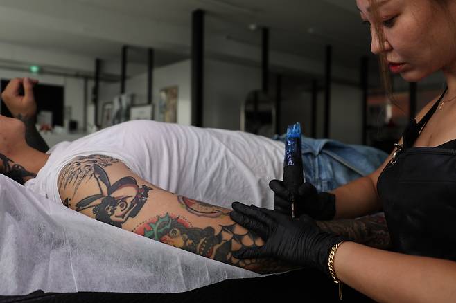 A person gets a tattoo done by a tattoo artist in downtown Seoul on Aug. 27. [YONHAP]