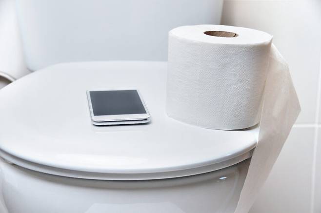 화장실에서 스마트폰을 사용하는 습관이 무의식적으로 변기에 앉아있는 시간을 늘려 치질 위험을 높일 수 있다는 점이 밝혀졌다. [사진=게티이미지뱅크]