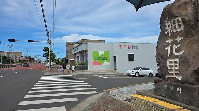 외국인 관광객 일행이 인근 올리브영 매장에서 쇼핑을 마치고 걸어 나오고 있는 모습. 마을 입구 표지석 바로 옆에 유명 프랜차이즈 카페 건물이 있다.