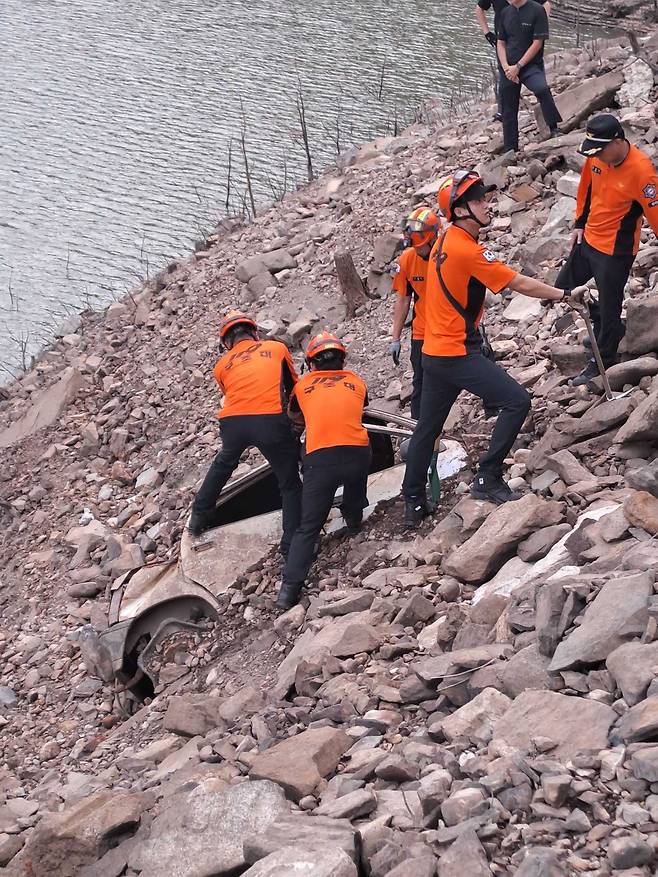 119 구조대원들이 지난 3일 오후 5시 32분쯤 강원 강릉시 오봉저수지의 경사면에서 발견된 차량 내부와 주변지역을 수색하고 있다. 강원도소방본부 제공