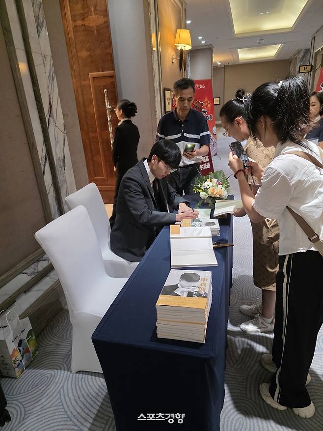 신진서 9단이 지난 2일 중국 칭다오 쉐라톤 칭다오 자오저우 호텔에서 열린 제27회 농심신라면배 세계바둑최강전 사전 기자회견이 끝난 뒤 팬들이 가져온 자서전에 사인을 하고 있다. 칭다오 | 윤은용 기자