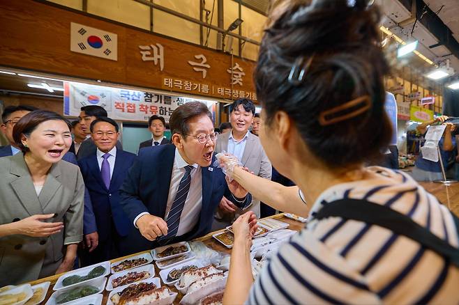 이재명 대통령이 5일 인천 미추홀구 용현시장을 방문해 상인이 건낸 떡을 시식하고 있다. 대통령실 제공