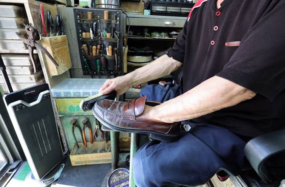 A cobbler surnamed Jo polishes a customer’s shoes in central Seoul on Sept. 1. [KANG JUNG-HYUN]